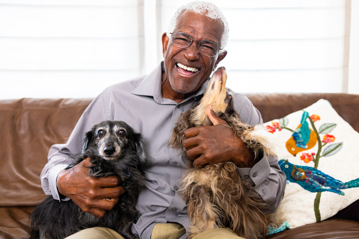 man sitting on sofa with 2 dogs