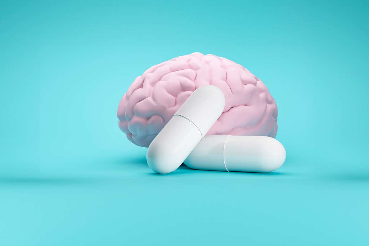 Brain and two white pills in front of a blue background