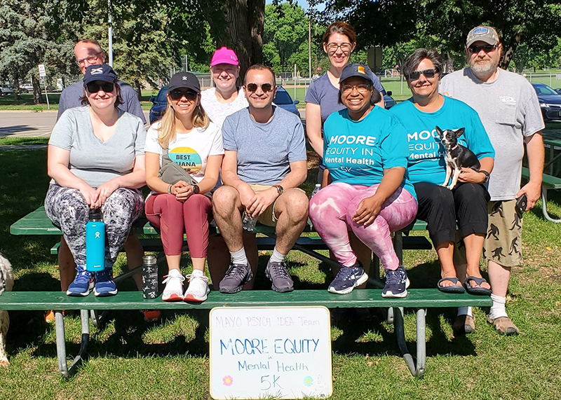 participants in their home community pose with a sign for the Mayo Psych IDEA Team