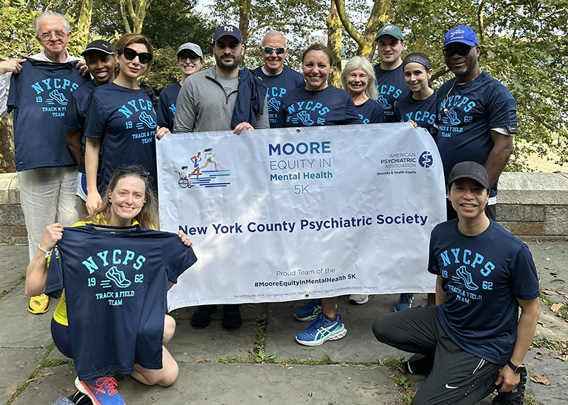 participants in their home community  pose with a sign for the New York County Psychiatric Society