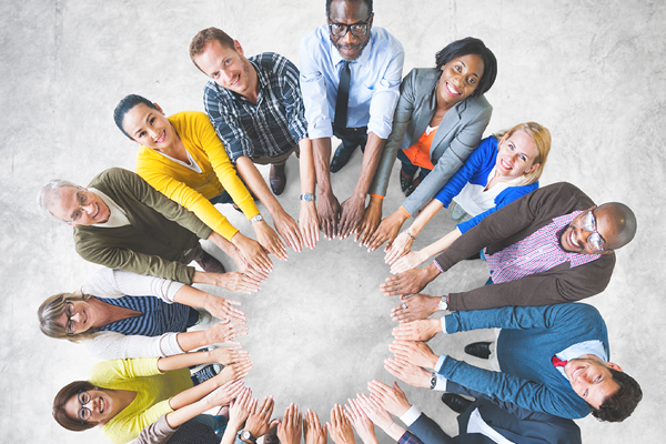 Overhead view of a diverse group of people looking up and forming a circle with their arms outstretched.