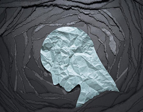 A crumpled-paper silhouette of a human head facing downward, set against a dark, layered background