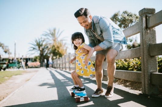dad helping daughter with skateboarding