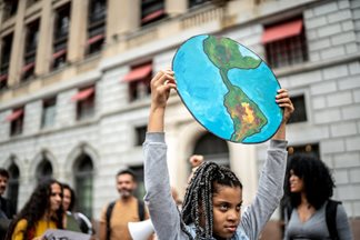 Adults and youth at a climate protest, girl holding image of the earth