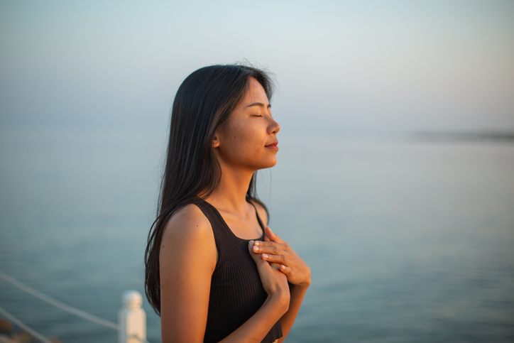woman praying or contemplating by a lake