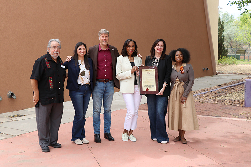 Group of community leaders and organizers pose together, displaying a framed recognition certificate