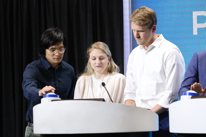 Winning team members Daniel Liaou, M.D., Caroline McCool, M.D., Ph.D., and  Hunter Hinman, M.D., answer questions at the podium during the live MindGames competition