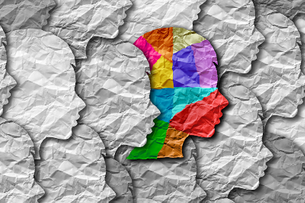Multicolored head silhouette stands out against a background of monochrome crumpled paper profiles