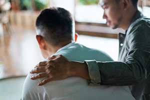 man with hand on other man's shoulder