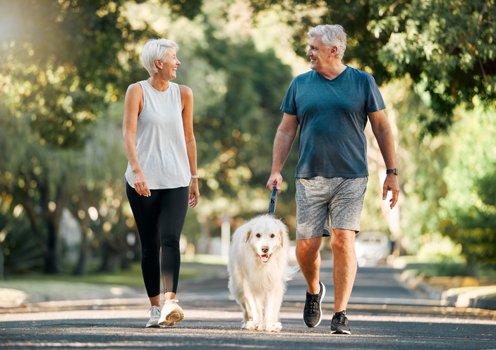 2 older adults walking a dog