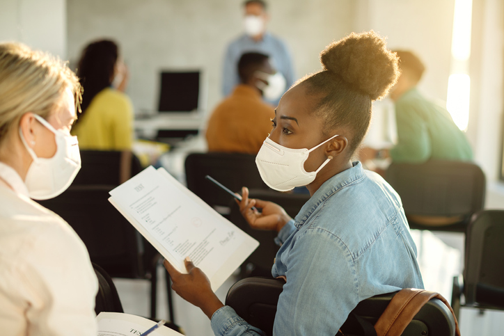 Two young female student wearing medical masks in class