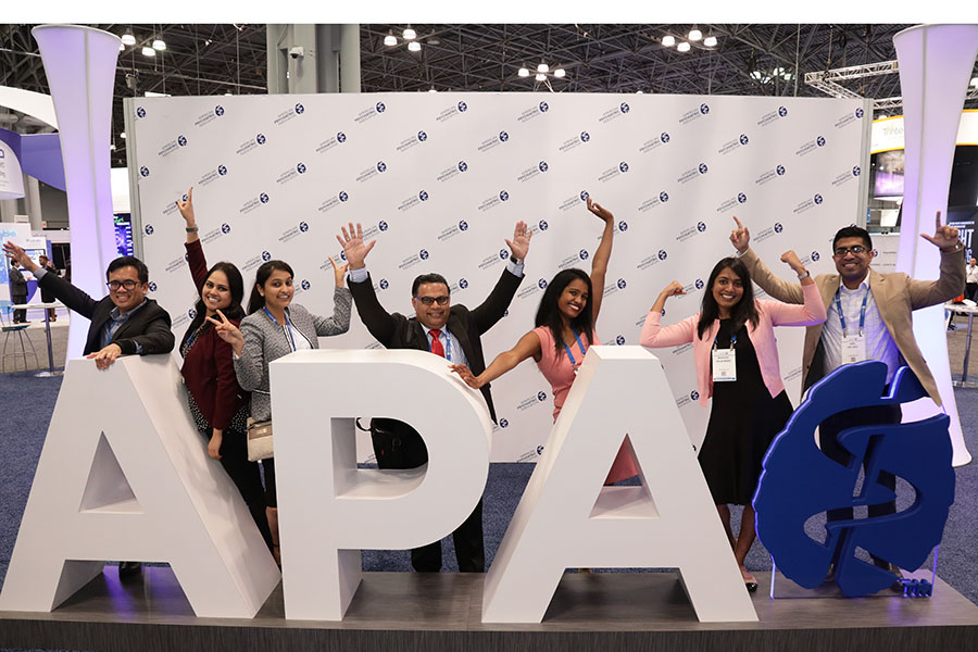 Group of people posing for photo in front of APA Logo