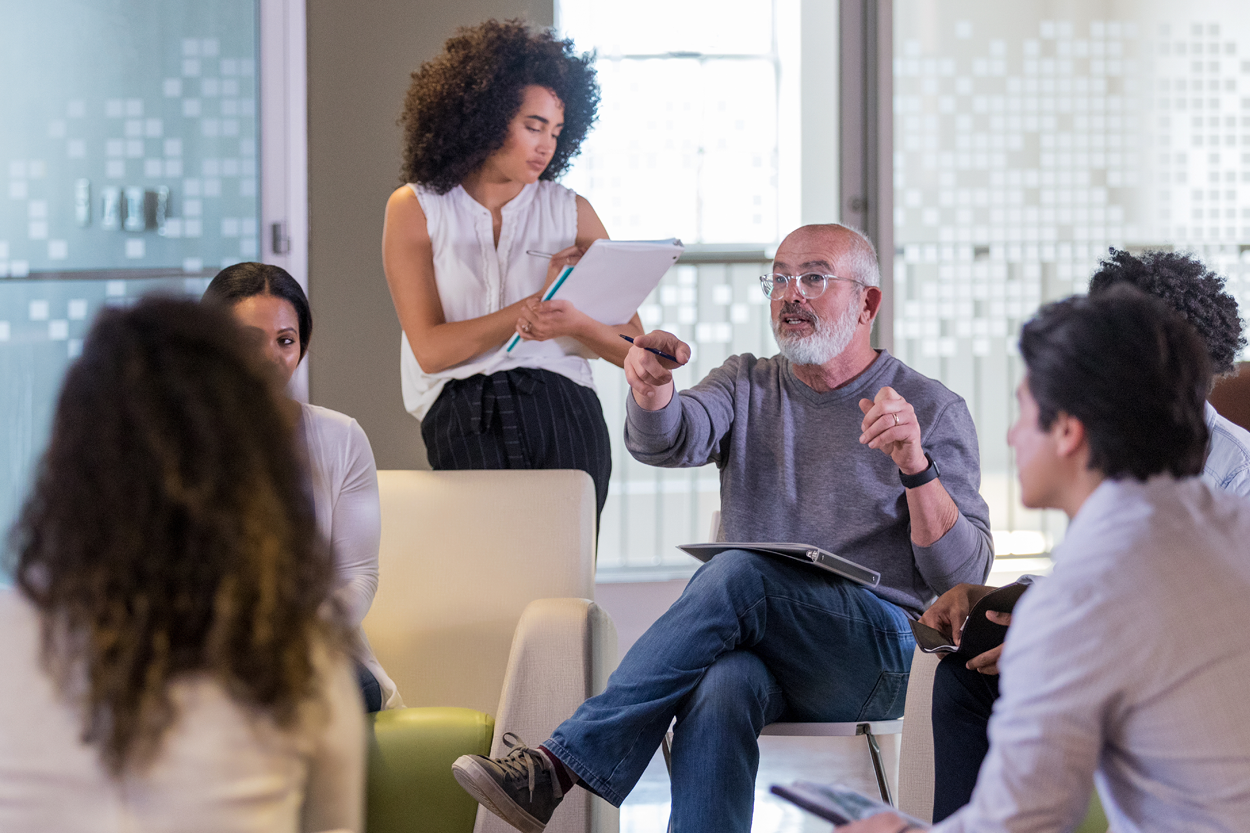 A group of seated and standing individuals in discussion.